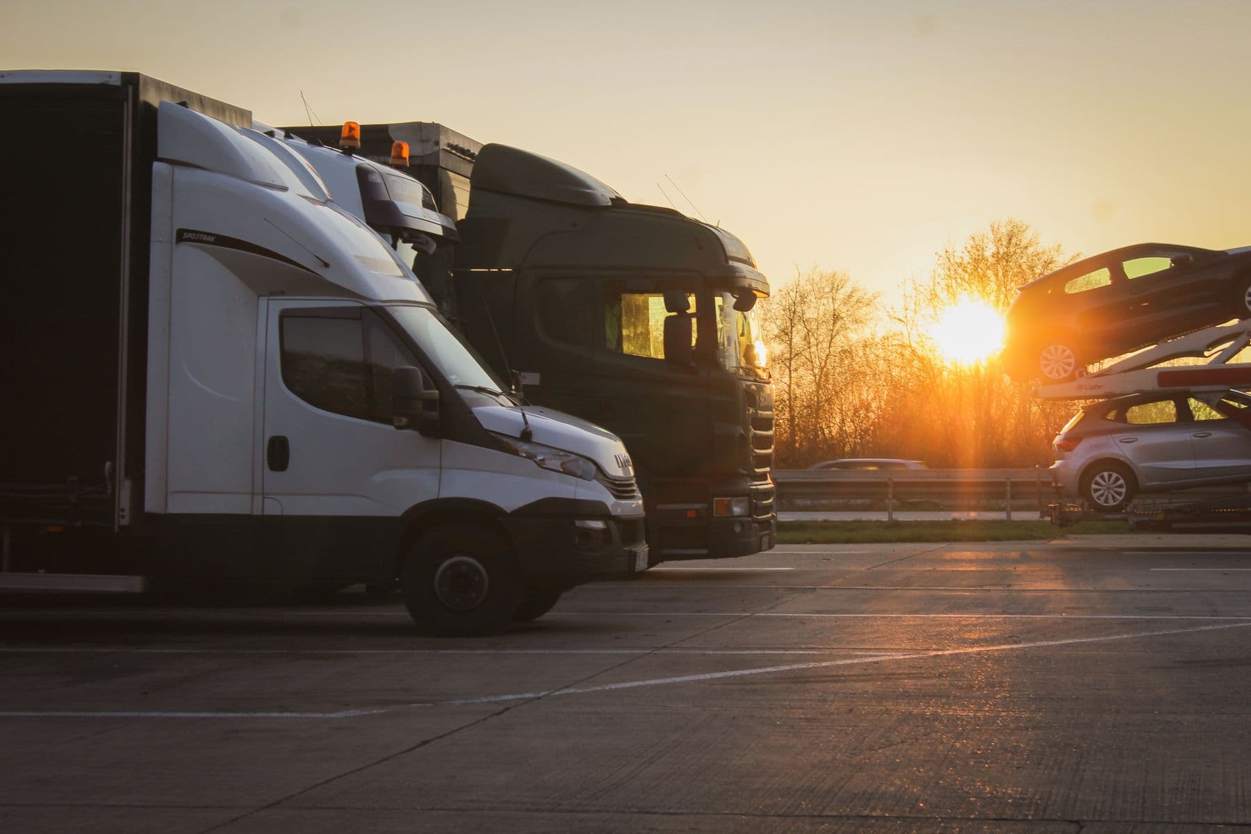 European freight trucks and a loaded vehicle transporter at sunset